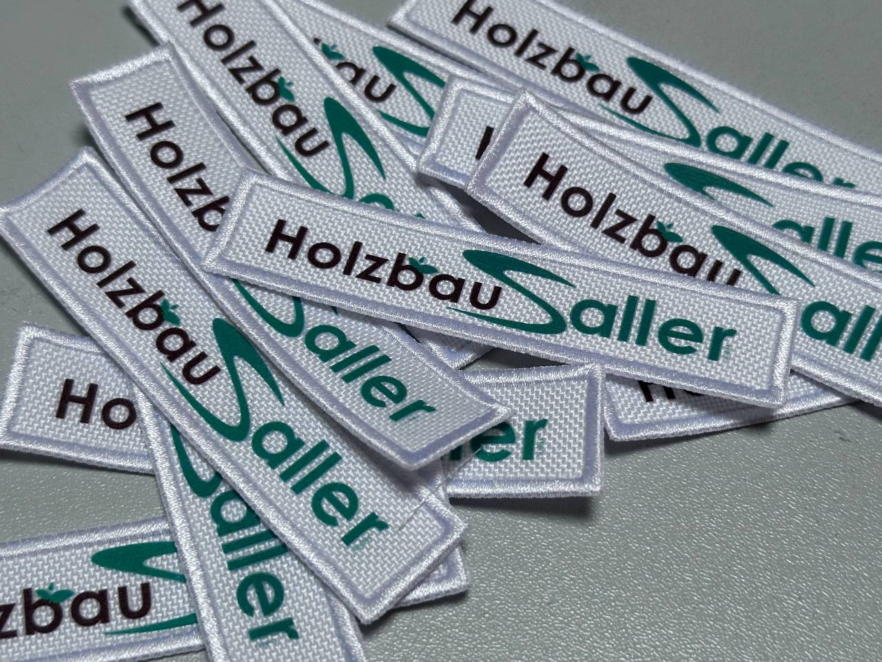 Weiße gewebte Firmenlabels mit grüner und schwarzer Schrift