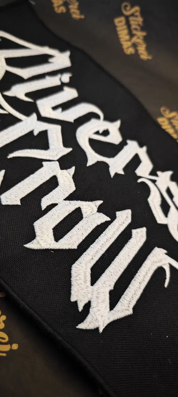 Großer gestickter Schriftzug weiß auf schwarz – Gothic-Lettering Detail