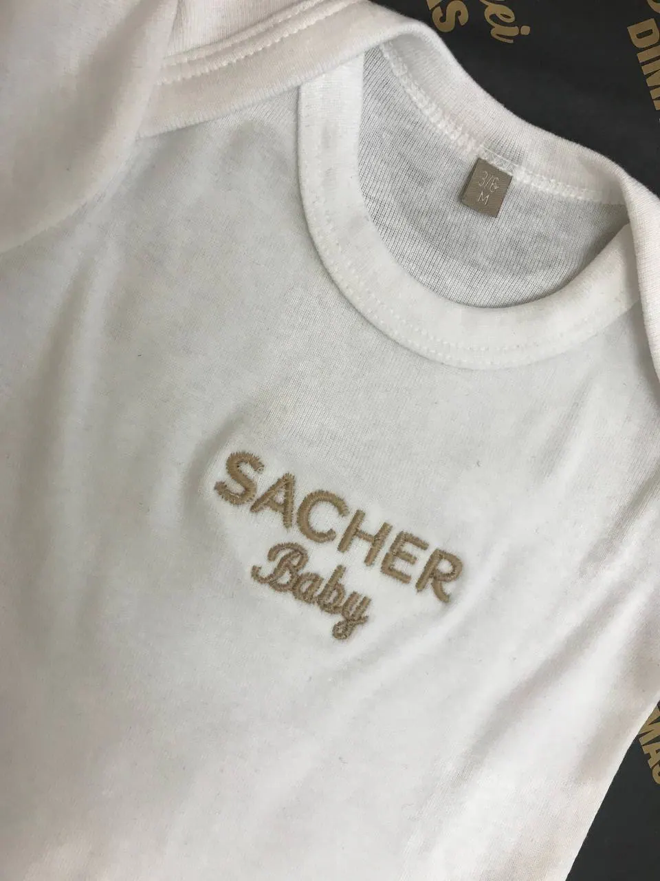 Sacher Baby bestickter Baby-Body weiß – feine Goldstickerei auf Textil