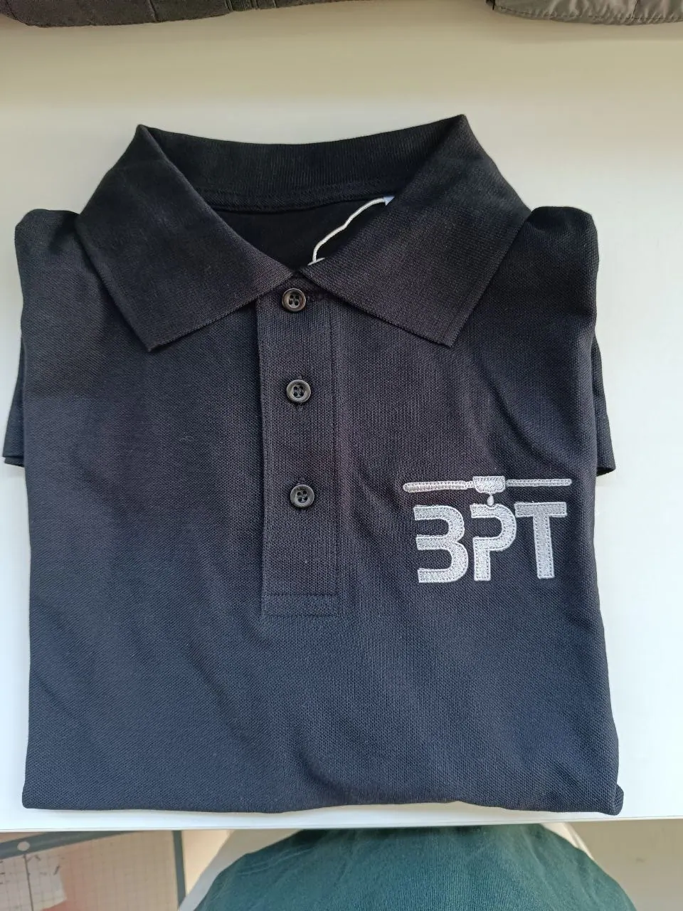 Schwarzes Poloshirt mit gesticktem BPT Logo in silber – Detailaufnahme Brustlogo