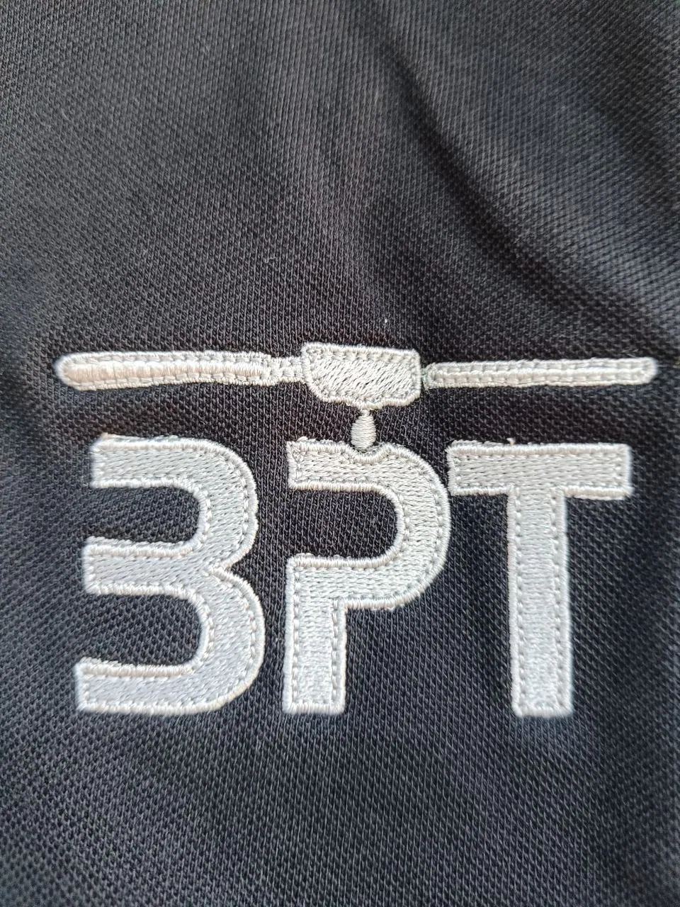 Detail BPT Firmenlogo silbergrau gestickt auf schwarzem Pique-Polo