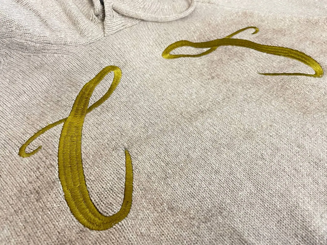 Goldene Initialen-Stickerei auf beigem Pullover – elegante Buchstaben bestickt