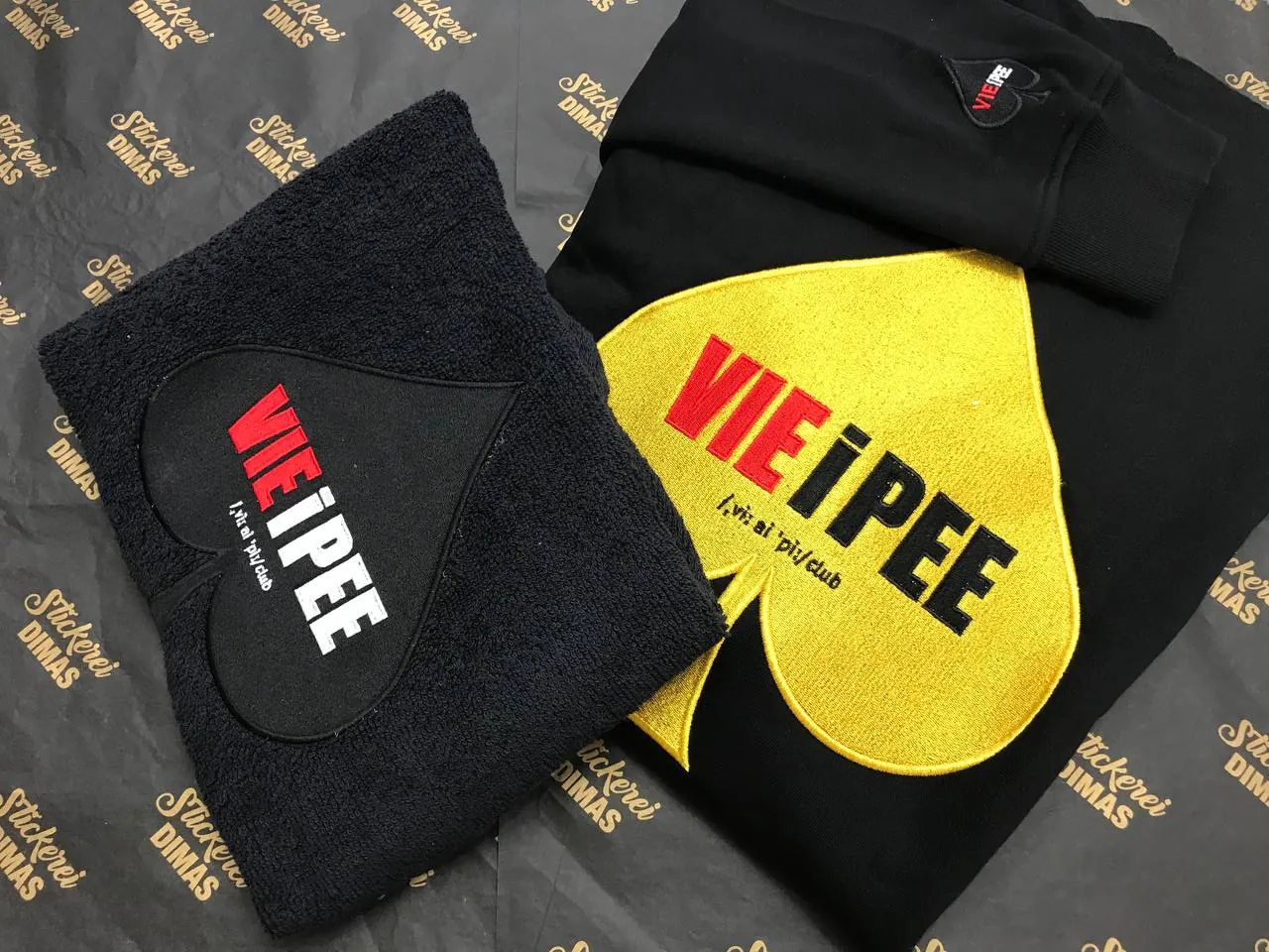 VIE iPEE Club bestickter Hoodie und Handtuch – Logo-Stickerei schwarz-gold-rot
