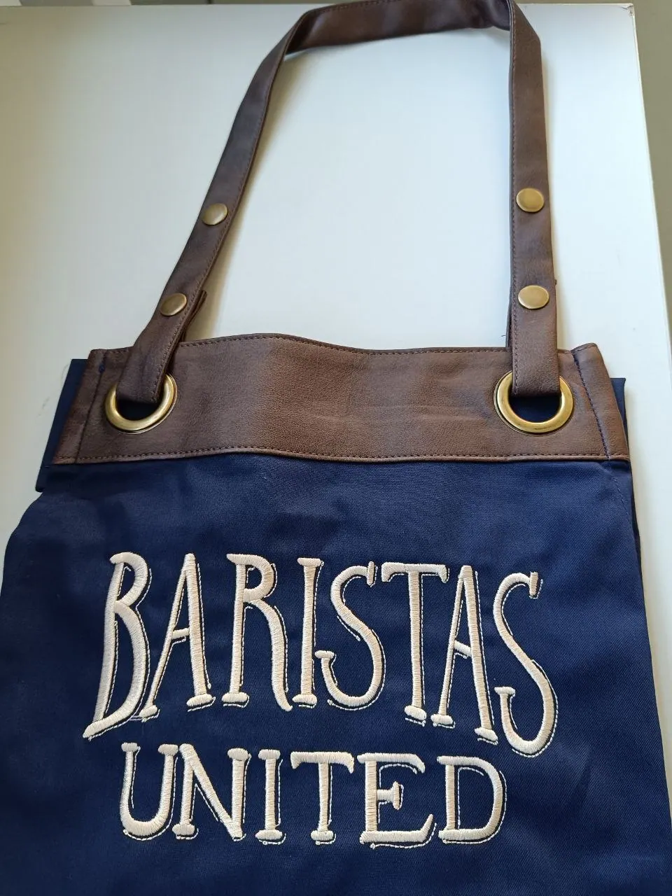 Navy Schürze mit Leder-Brustlatz und gesticktem Baristas Logo, hochwertige Gastro-Schürze