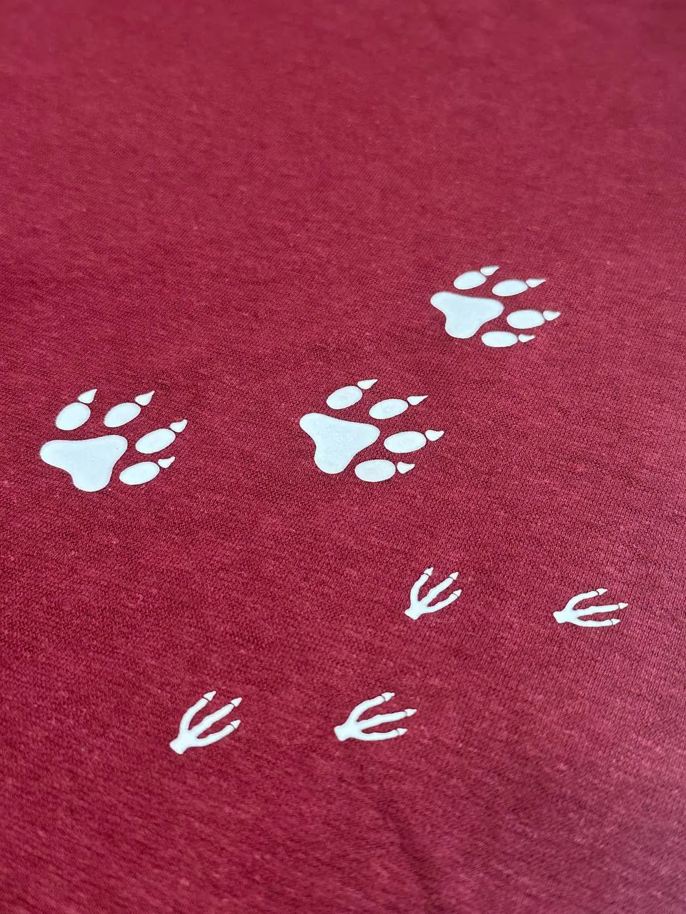 Tierpfoten und Vogelspuren bedruckt auf rotem T-Shirt – Textildruck weiß