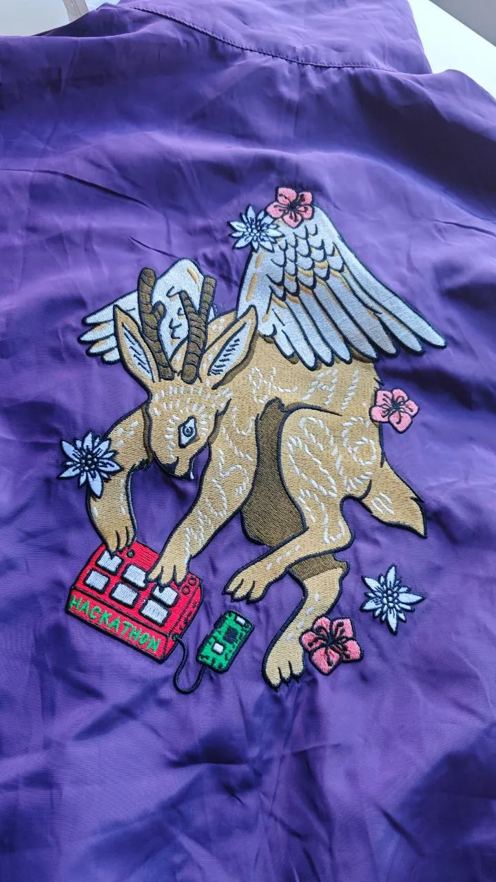 Großflächige Rückenstickerei Hackathon Steinbock mit Flügeln auf violettem Sukajan – Custom Stickmotiv mit Edelweiß