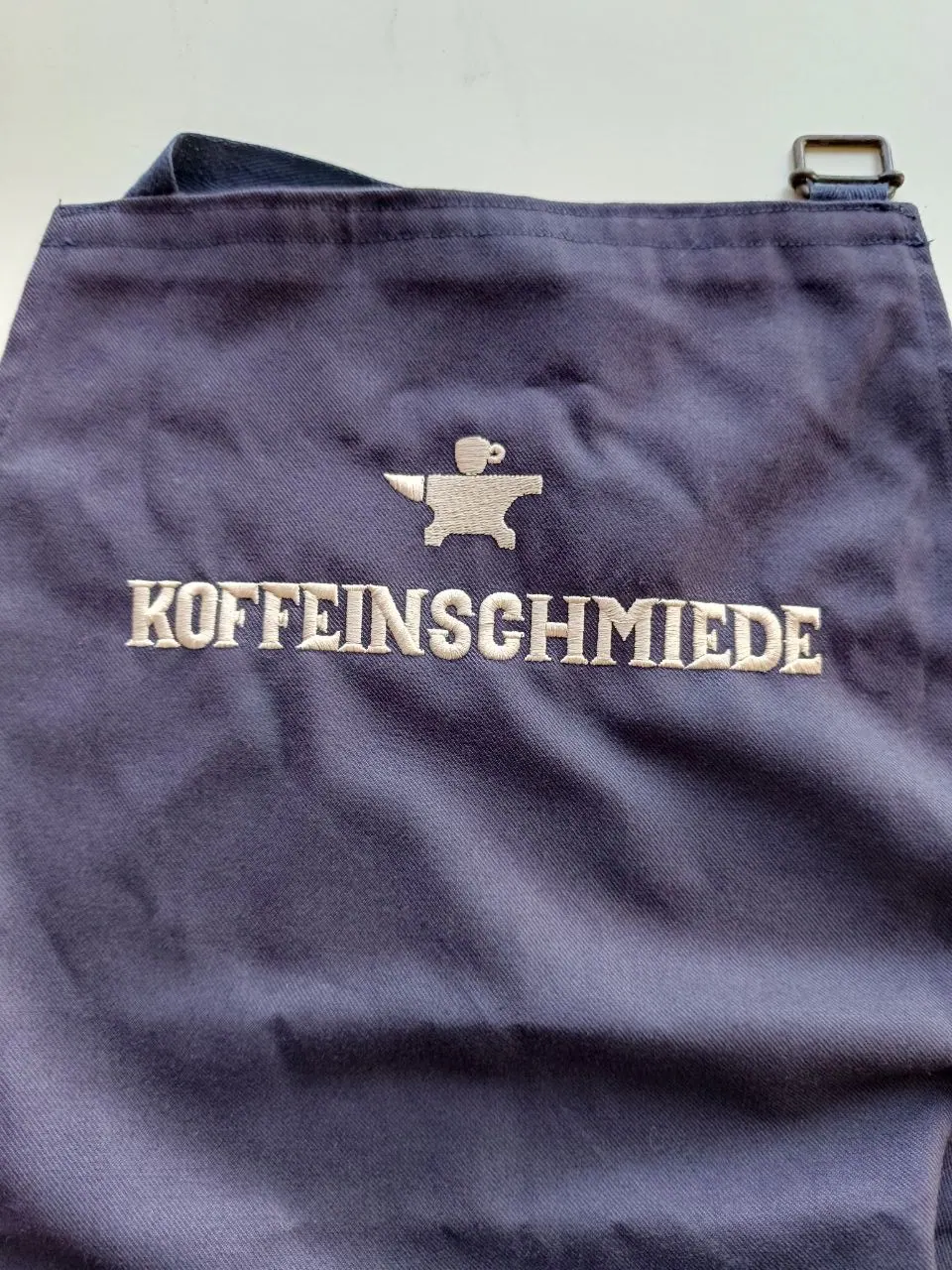 Schwarze Schürze mit gesticktem Koffeinschmiede Logo für Café-Personal