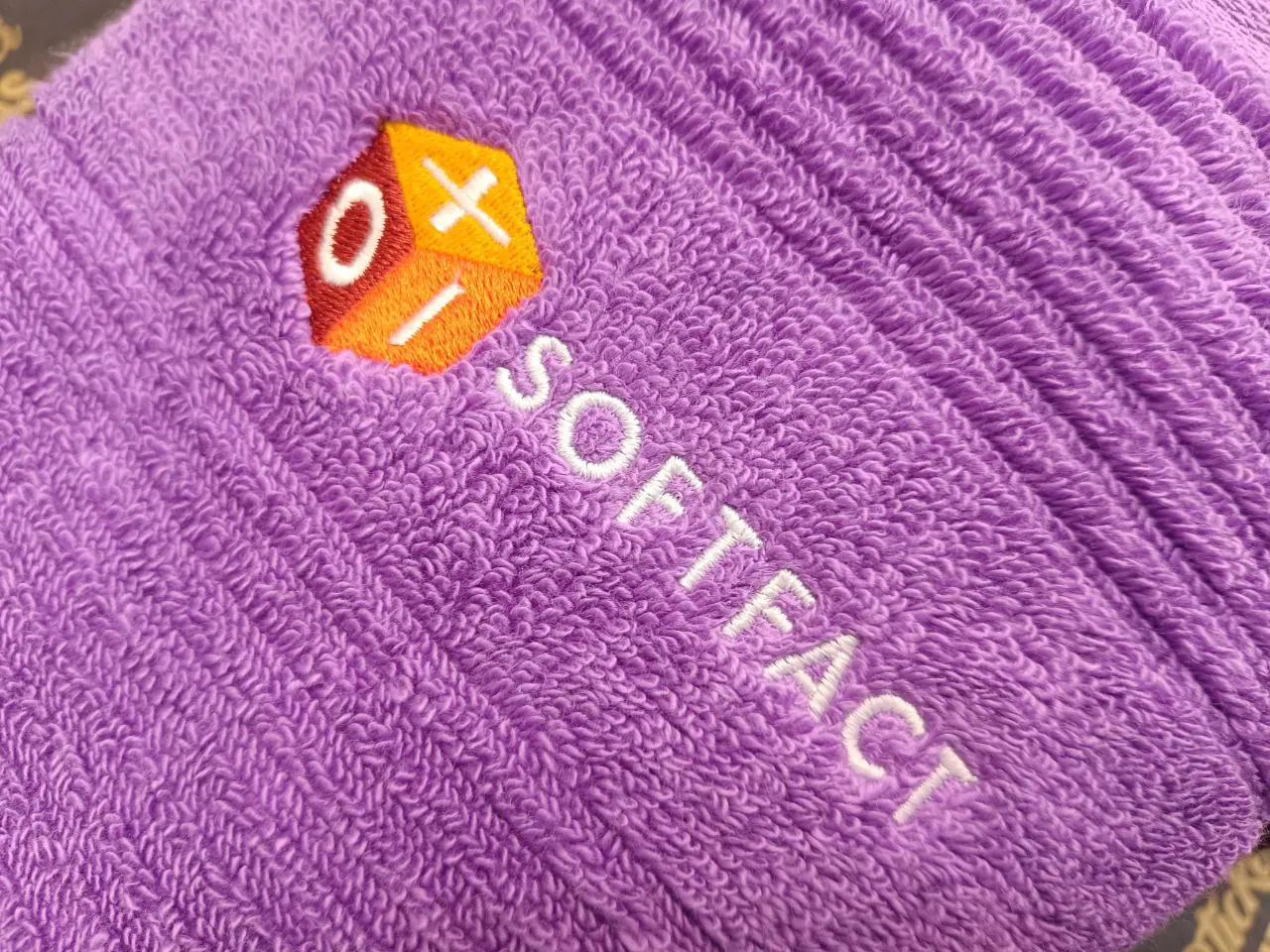 Softfact Logo-Stickerei auf lila Frottee-Handtuch – Firmenlogo bestickt