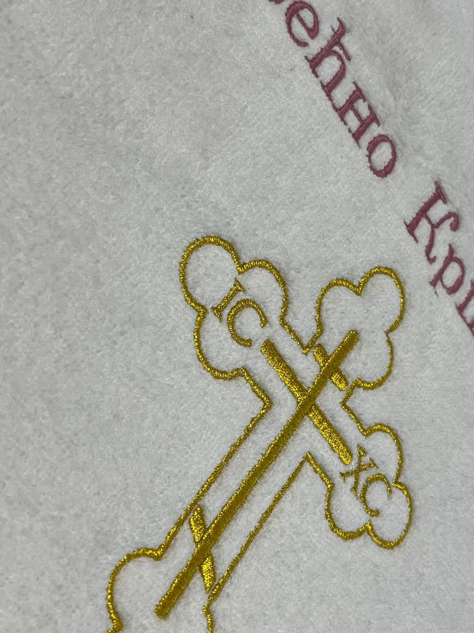 Goldenes orthodoxes Kreuz gestickt auf weißem Taufgewand – Detail Kreuzstickerei
